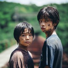 Two boys covered in mud gaze mysteriously at the camera.