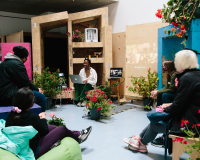 A group of people sitting in a workshop room filled with plants