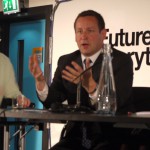 Ed Vaizey, Minster for Culture, Communications and Creative Industries at DCMS sitting at a table speaking animatedly - there is a sign behind him, just readable, which says Future Everything.