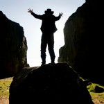 Jez in on a rock, back to the camera, framed between two cliff walls on Ilkley Moor.