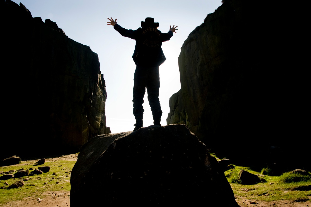 Jez in on a rock, back to the camera, framed between two cliff walls on Ilkley Moor.