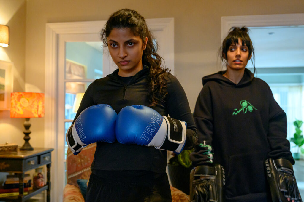 Woman wearing blue boxing gloves. A still from Polite Society