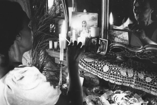 Still from Passion for Remembrance - a woman sits at an alter . the image is black and white