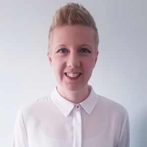 head shot of talent exec Alix Taylor. She stands centrally in a white room wearing a white shirt. visible from shoulders up she is smiling, white with short blond hair.