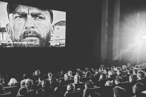 A black and white image of people sat watching a film
