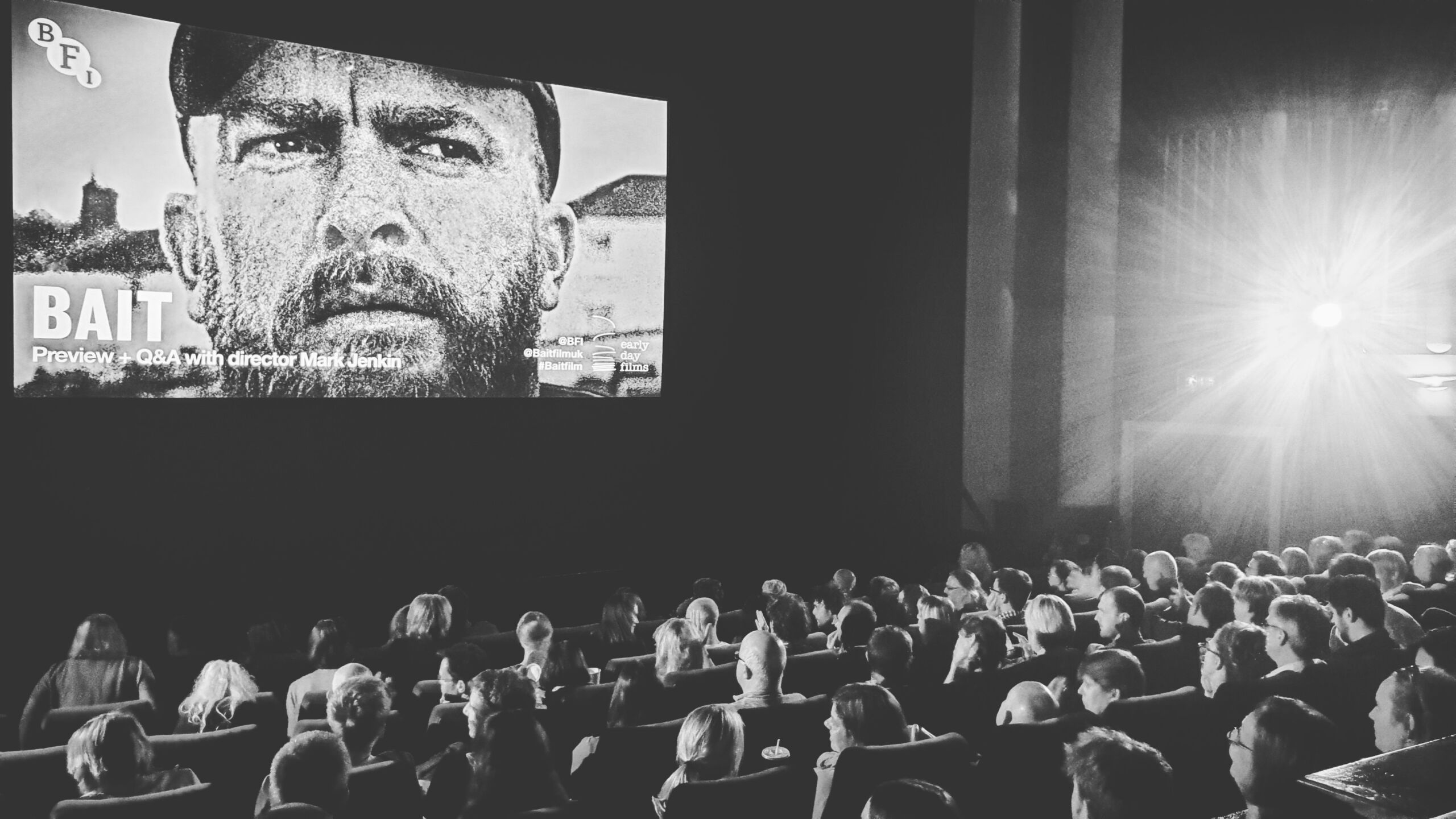 A black and white image of people sat watching a film