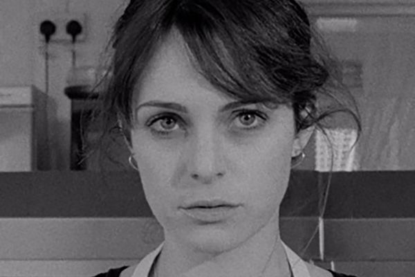 black and white image of a woman staring at the camera, she has a concerned look and dark straight hair. image is a still from the short film HARD, CRACKED THE WIND.