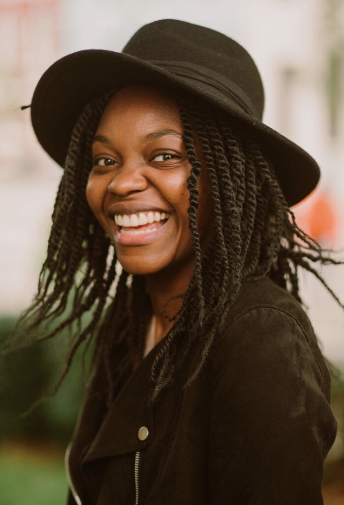 headshot of Mevis Birungi. she smiles, wearing a black shirt and har
