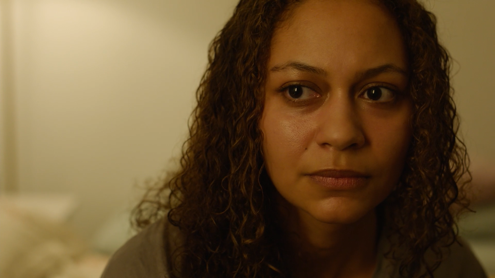 Close up of a woman who gazes into the distance. she is inside, warmly lit