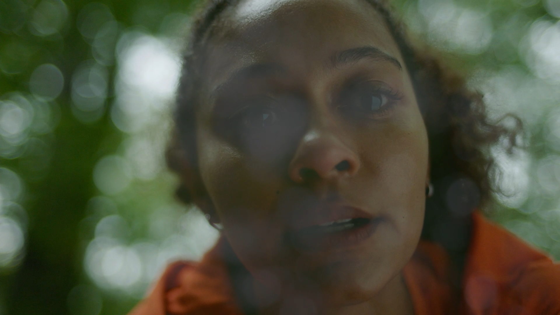 close up of a woman face, she appears to merge into the forest around her