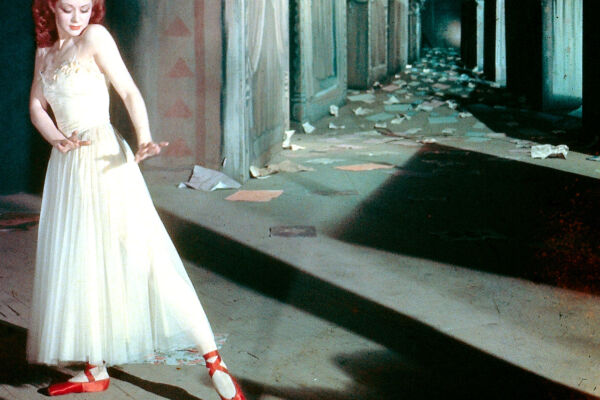 A still from Red Shoes with a ballet dancer striking a pose looking at her striking red shoes.