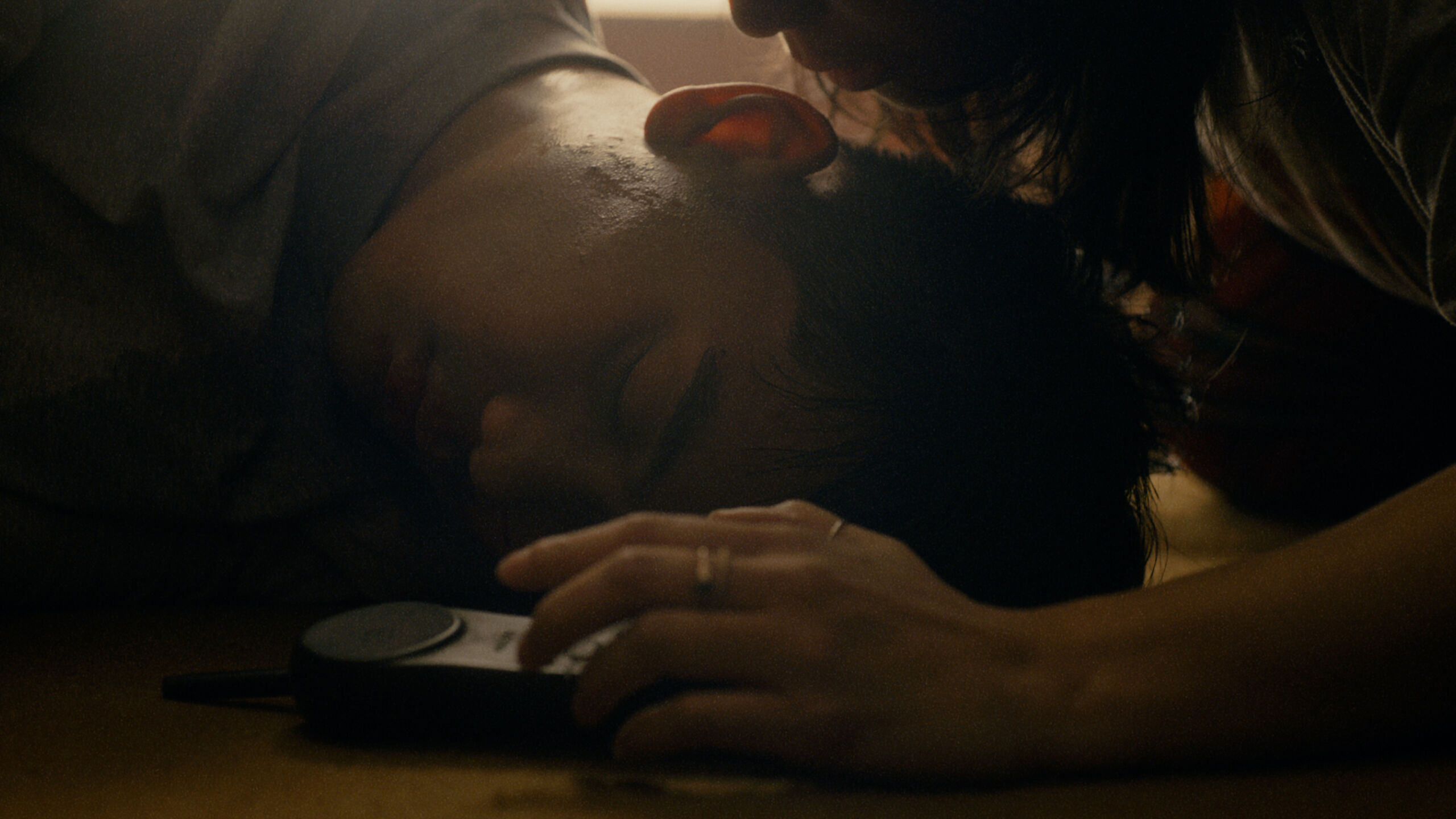 close up of a mans head on the floor. in dark room , a woman leans over him