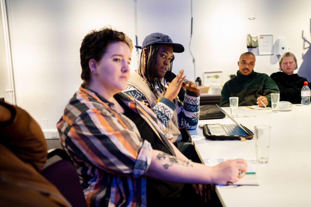 Jojo and Penn sit together and Jojo is asking a question. Two other eople are in the background.