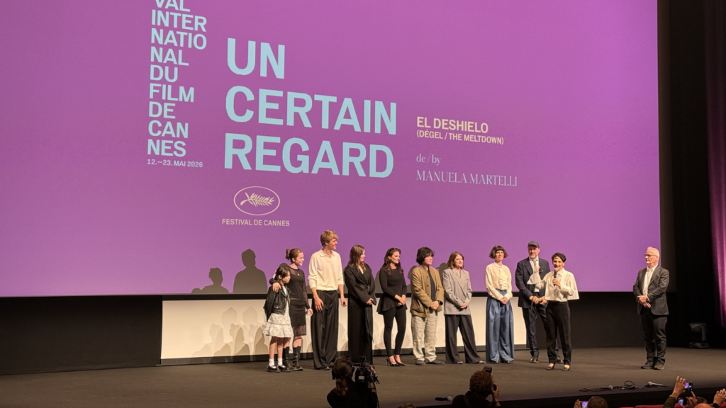 A group of people stand on stage in front of a purple cinema screen at Cannes Film Festival. The screen reads: Un Certain Regard