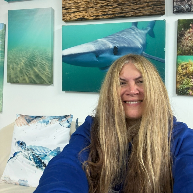A woman smiling in front of pictures of sea creatures