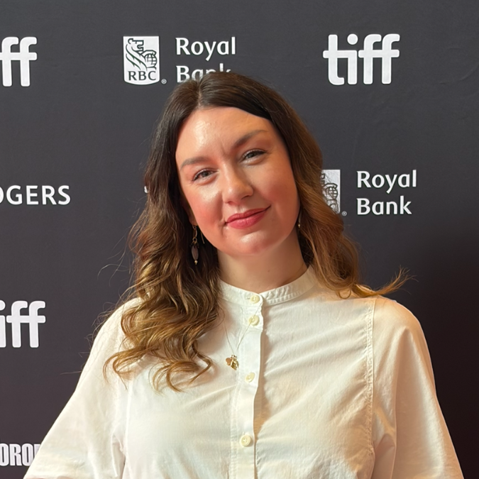 A person smiling in front of a tiff step and repeat