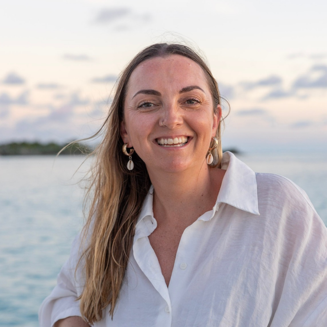 woman smiling beside sea at sunset