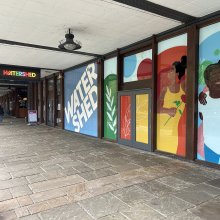 Exterior shot of Watershed front door with murals of people across the glass front.