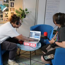 Two young white people wearing headphones connect to a silver macbook air.