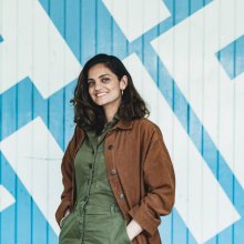 Photo of Nida Manzoor standing in front of a large Watershed logo.