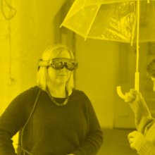 Two people one wearing a VR head set the other holding an umbrella