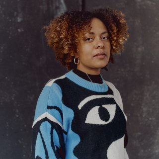 Photo of a black woman wearing a blue, black and white jumper