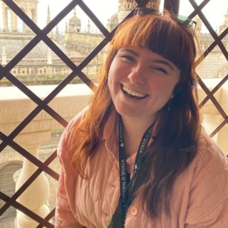 Portrait of a white woman in her 20s laughing whilst looking at the camera