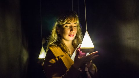 A woman's face is illuminated by a triangular light.