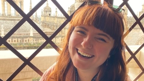 Portrait of a white woman in her 20s laughing whilst looking at the camera